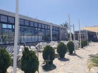 eine Terrasse mit Stühlen und Bäumen vor einem Gebäude in der Unterkunft Apartament Palm Bay View Esentepe Bahceli in Kyrenia