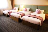 a hotel room with three beds with pink pillows at Fushin Hotel - Tainan in Tainan