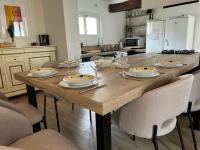 a kitchen with a wooden table with plates and wine glasses at Charmante Maison proche Chartres in Lèves