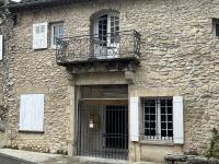 a stone building with a balcony and a door at Sur le Pont in Vaison-la-Romaine