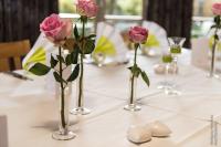 a table with pink roses in vases on it at Flair Hotel Dobrachtal in Kulmbach