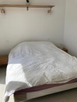 a bed with white sheets on it in a room at Studio à louer style loft in Mantes-la-Jolie
