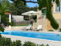 two chairs and an umbrella next to a swimming pool at Villa Yucca Istra in Labin