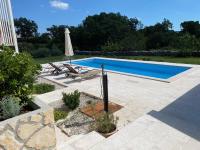 a swimming pool with two chairs and an umbrella at Villa Yucca Istra in Labin
