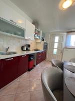 a kitchen with red cabinets and a sink and chairs at Denis Apartment in Ždrelac