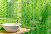 a green tiled bathroom with a sink and a shower at Zenitude Hôtel-Résidences Nantes Métropole in Nantes