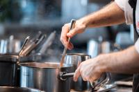 a man stirring a pot in a kitchen at Warsaw Presidential Hotel in Warsaw