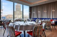 a dining room with tables and chairs and large windows at Warsaw Presidential Hotel in Warsaw