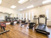 a gym with several treadmills and cardio machines at Mercure Cardiff North Hotel in Cardiff