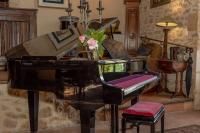 a black piano in a room with a vase of flowers at Gîtes et chambres croix du sud in Saint-Amand-de-Vergt