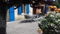 una mesa y sillas frente a una casa con puertas azules en Gîte Le Laurentin, en Saint-Laurent-du-Plan