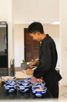 Um homem em pé em frente a tigelas azuis sobre um balcão. em Khla Lodge em Kampot