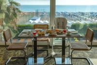 リッチョーネにあるHotel Fedora Riccione - FRONTE MAREのビーチを望むテーブルと椅子