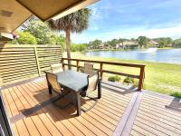eine Holzterrasse mit einem Tisch, Stühlen und einem See in der Unterkunft 5191 Beachwalk in Destin
