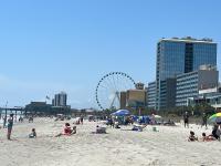 eine Gruppe von Menschen am Strand mit einem Riesenrad in der Unterkunft Oceanfront Luxury 2BR King Suite Atlantica Resort in Myrtle Beach