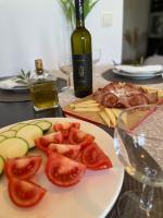 a plate of tomatoes and cheese and a bottle of wine at Denis Apartment in Ždrelac