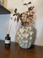 a white vase with flowers in it next to a bottle at Denis Apartment in Ždrelac