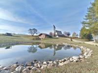 a pond in front of a house with a church at La Capanna in Margno