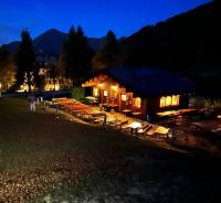 a log cabin with tables and chairs at night at La Capanna in Margno