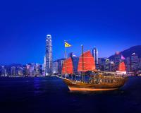a boat with red sails in the water with a city at Four Seasons Hotel Hong Kong in Hong Kong