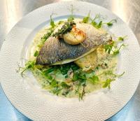 a plate of food with fish on top of mashed potatoes at The Gate Hangs High in Hook Norton