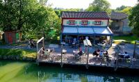 a group of people standing outside a building next to a river at Une bouteille au canal in Dieupentale