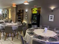 Un comedor con mesas y sillas con copas de vino. en LOGIS HOTELS - Hôtel et Restaurant L'Océana, en Lanton