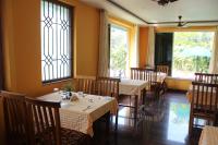 een eetkamer met tafels en stoelen en ramen bij Chrisander's Resort in Quepem