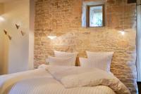 a bedroom with a bed with a stone wall at Maison Lou Piade in Sarlat-la-Canéda