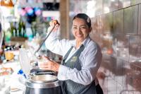 Una mujer en una cocina revolviendo una olla en Hotel Obelisco, en Cali