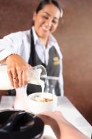 una mujer vertiendo leche en un tazón de comida en Hotel Obelisco, en Cali