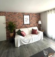 un sofá blanco en una sala de estar con una pared de ladrillo en Superbe Rez-de-Villa 6p calme &amp; plage à pied, en Le Pradet