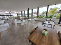 ボゴールにあるHOTEL & WISMA BINTANG JADAYATのテーブルと椅子と窓がある空のレストラン