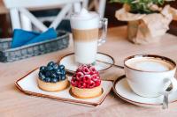 two cups of coffee and two pastries on plates on a table at Hotel Szydłowski in Gdańsk