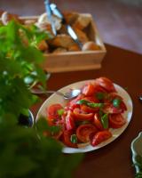 タラスコンにあるMas des Comtes de Provenceのテーブルの上にはトマトの皿とパンの箱が置かれている