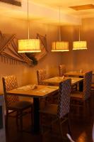 Un comedor con mesas y sillas de madera y luces. en Hotel GH Guaparo Suites Valencia, en Valencia