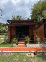 ein kleines Backsteinhaus mit einer Veranda und einigen Pflanzen in der Unterkunft Red Coral Cottage in Tanjung Rhu