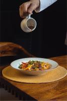 una persona vertiendo salsa en un plato de comida en Aura Boutique Hotel, en Udaipur