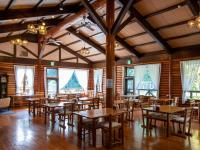 Un restaurante con mesas y sillas de madera y ventanas. en 宝泉坊ロッジ, en Kami-ōno