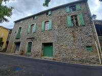 an old stone building with green doors and windows at L&#39;Armandière, maison de caractère où règne calme et sérénité. in Pézenes-les-Mines