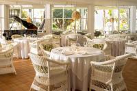 ein Restaurant mit weißen Tischen und Stühlen und einem Klavier in der Unterkunft Melia Cala d'Or Boutique Hotel in Cala d´Or
