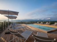 a swimming pool with chairs and umbrellas on a deck at ibis Styles Porto Vecchio in Porto-Vecchio