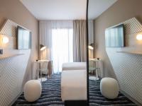 a hotel room with two beds and a mirror at ibis Styles Porto Vecchio in Porto-Vecchio