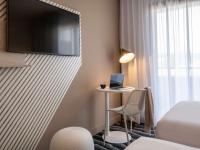a hotel room with a desk and a tv on a wall at ibis Styles Porto Vecchio in Porto-Vecchio