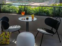 a table and chairs on a balcony with a drink at ibis Styles Porto Vecchio in Porto-Vecchio