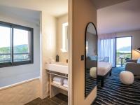 a hotel room with a bed and a sink and a mirror at ibis Styles Porto Vecchio in Porto-Vecchio