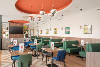 a dining room with tables and green chairs at Holiday Inn Norwich City by IHG in Norwich