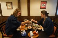 duas mulheres sentadas à mesa comendo com pauzinhos em Kazeya em Takayama