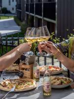 Dos personas sosteniendo copas de vino en una mesa con pizzas. en Vertshuset Konow, en Bergen