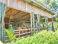 LulongoにあるTilapia Lodgeのテーブルと椅子が置かれたポーチのある木造住宅